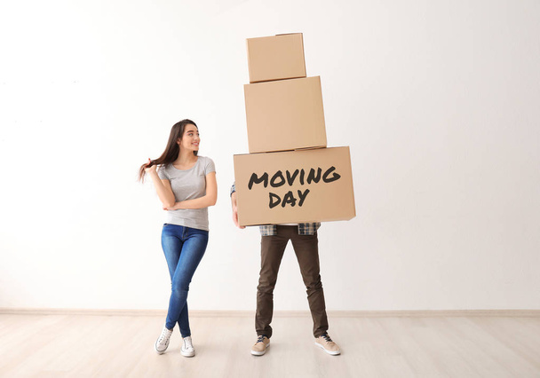Jovem casal com caixas de papelão em novo apartamento vazio no dia em movimento
 - Foto, Imagem