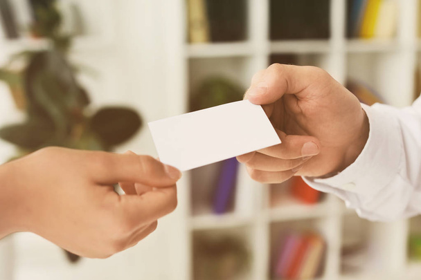 Man giving business card to woman in office, closeup - Foto, afbeelding