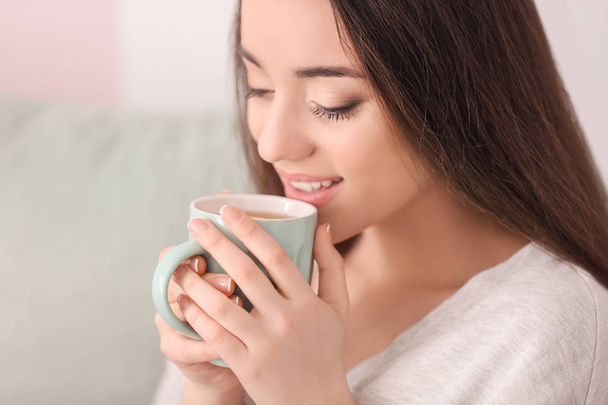 Kaunis nuori nainen kupin kuumaa teetä kotona
 - Valokuva, kuva