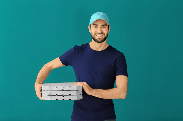 Delivery man with cardboard pizza boxes on color background - Photo, Image