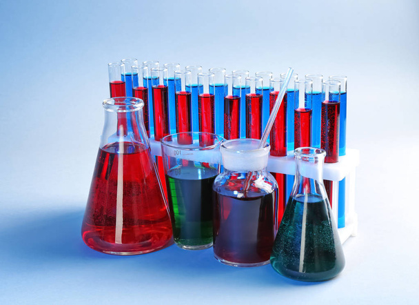 Хімічний скляний посуд з різними рідинами на кольоровому фоні
 - Фото, зображення