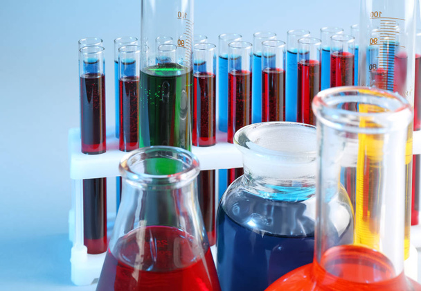 Chemische glaswerk met verschillende vloeistoffen op kleur achtergrond - Foto, afbeelding