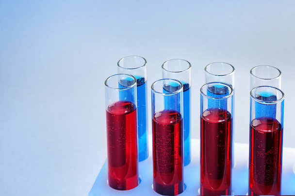 Reagenzgläser mit unterschiedlichen Flüssigkeiten auf farbigem Hintergrund - Foto, Bild