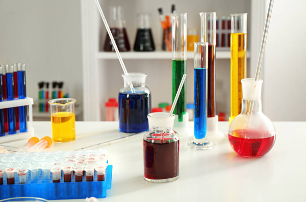 Chemische glaswerk met kleurrijke vloeistoffen op tafel - Foto, afbeelding