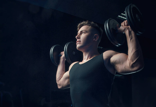 the sporty boy trains with dumbbells - Photo, Image