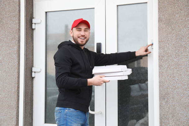 Mladý muž s lepenkové pizza krabice vyzváněcí zvonek venku. Donáška jídel - Fotografie, Obrázek