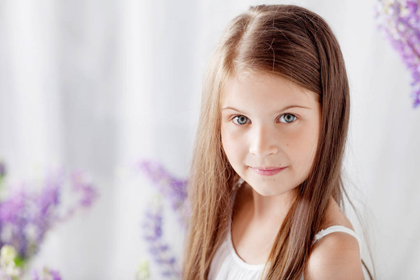 Portrait of pretty  little emotion girl  among violet flowers.Cl - Foto, afbeelding