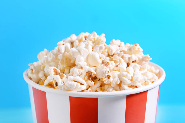 Papiereimer mit leckerem Popcorn auf farbigem Hintergrund, Nahaufnahme - Foto, Bild