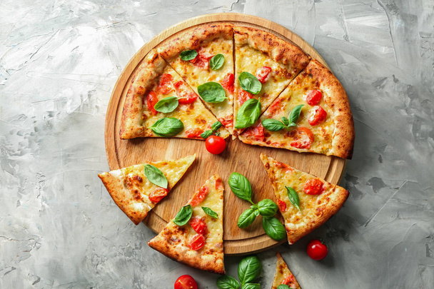 Tabuleiro com fatias de deliciosa pizza Margherita em fundo cinza
 - Foto, Imagem