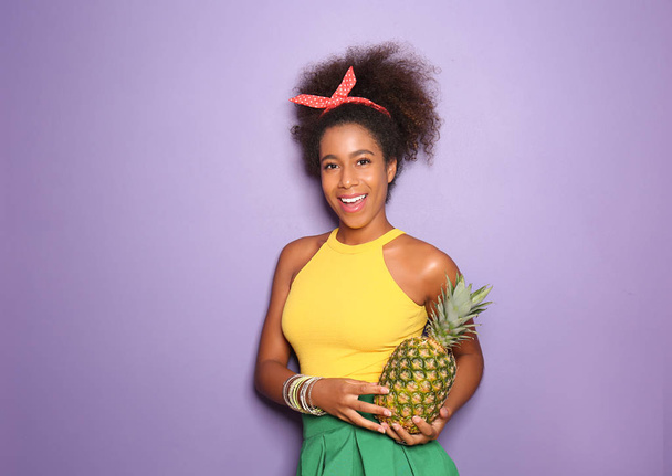 Beautiful African-American woman with pineapple on color background - Photo, Image