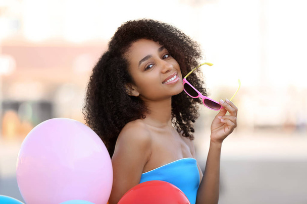 Beautiful African-American woman with balloons outdoors - Фото, зображення