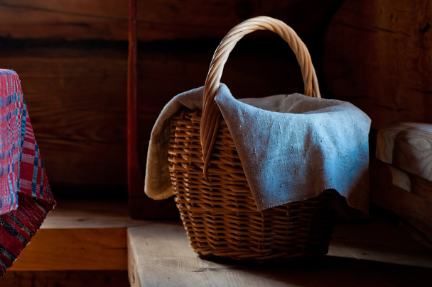 ψάθινο καλάθι με μια πετσέτα σε ένα ξύλινο παγκάκι σε ένα σπίτι του χωριού - Φωτογραφία, εικόνα