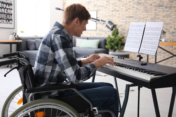 Evde synthesizer oynarken tekerlekli sandalyede genç müzisyen - Fotoğraf, Görsel