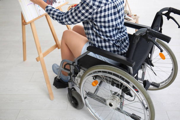 Joven artista femenina en silla de ruedas pintura cuadro en casa
 - Foto, imagen
