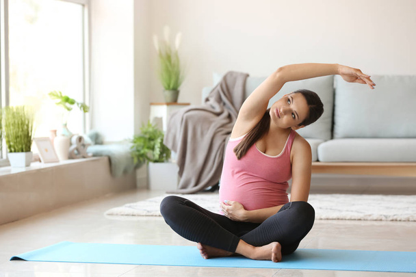 Mladá těhotná žena cvičí jógu doma - Fotografie, Obrázek