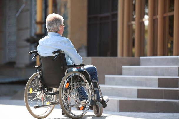 Старший в инвалидной коляске рядом с лестницей на открытом воздухе
 - Фото, изображение