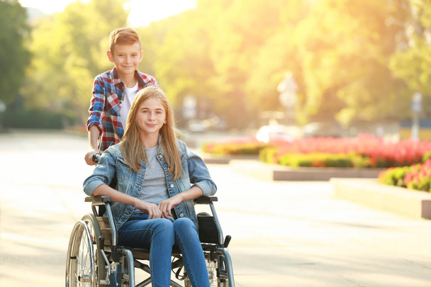 Έφηβη κοπέλα στο αναπηρικό καροτσάκι και τον αδελφό της σε εξωτερικούς χώρους - Φωτογραφία, εικόνα