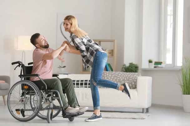Homme en fauteuil roulant avec belle femme dansant à la maison
 - Photo, image