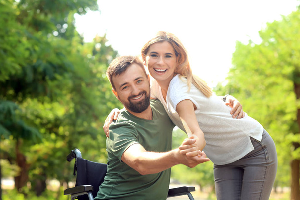 Homem em cadeira de rodas com bela mulher dançando ao ar livre
 - Foto, Imagem