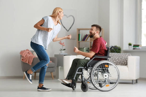 Mies pyörätuolissa kauniin naisen kanssa tanssimassa kotona
 - Valokuva, kuva