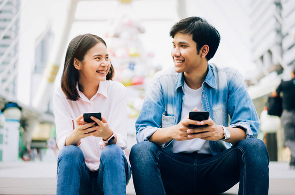 I giovani usano lo smartphone e sorridono mentre sono seduti sul tempo libero. concetto di tecnologia
 - Foto, immagini