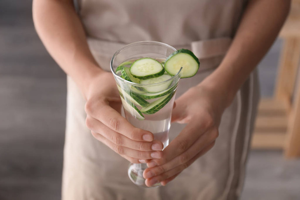 Woman holding glass with tasty fresh cucumber water, closeup - Photo, Image