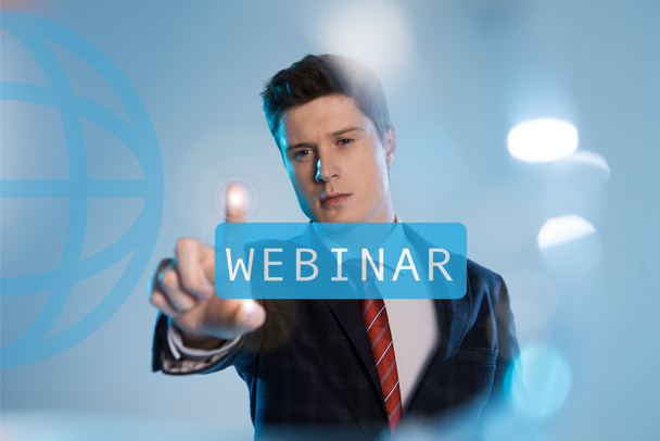 confident businessman in suit pointing at webinar illustration in front on blue background - 写真・画像