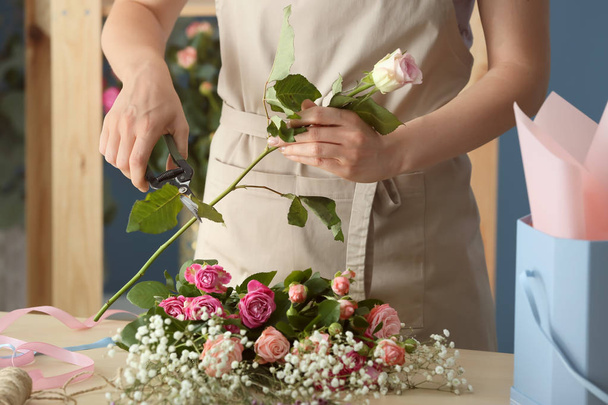 Female florist preparing bouquet of beautiful flowers at table - 写真・画像