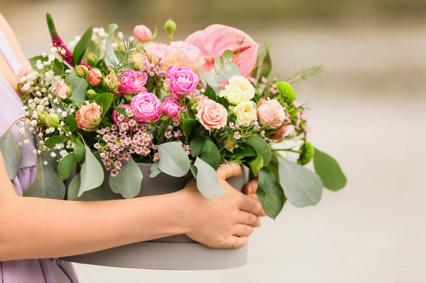 Woman holding gift box with beautiful flowers outdoors - Foto, imagen