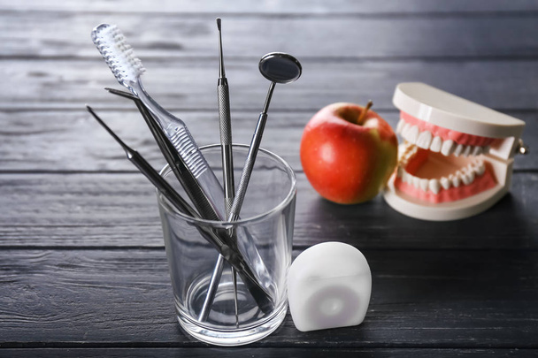 Kiillotus, lasi hammasharjalla ja hammasinstrumentit tummalla puupöydällä
 - Valokuva, kuva