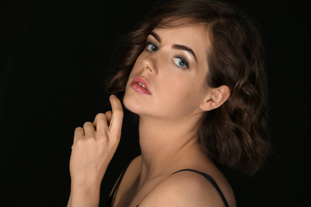 Portrait of beautiful young woman on dark background - Foto, Imagen