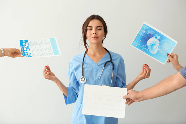 Krankenschwester mit viel Arbeit beim Meditieren auf hellem Hintergrund - Foto, Bild
