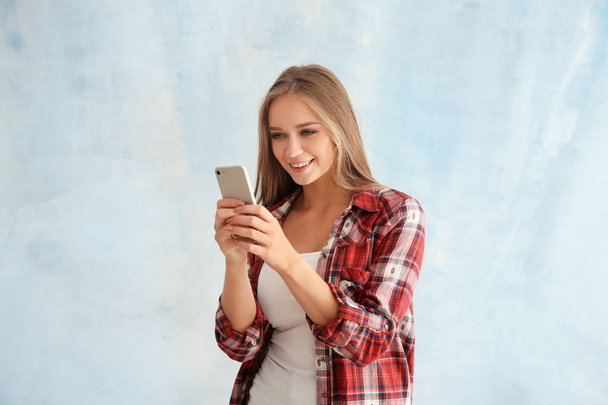 Young woman with mobile phone on light background - Foto, Imagen