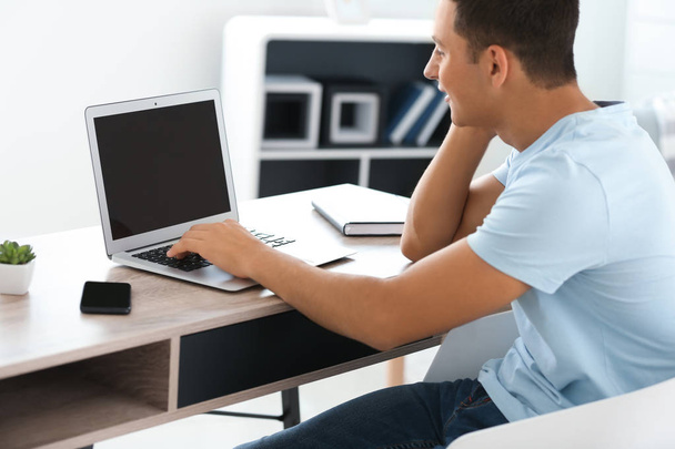 Hombre joven que trabaja con el ordenador portátil en casa
 - Foto, imagen