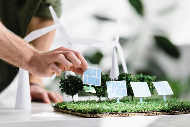 vista recortada del hombre poniendo paneles solares modelos sobre hierba en la mesa en la oficina
 - Foto, imagen