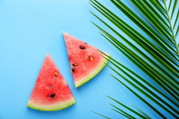Slices of ripe watermelon and tropical leaf on color background - Foto, immagini