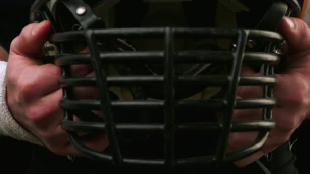 American football. American football player holds helmet with both hands. A big american football player. Preparing for the game. Training. Close-up, black background - Footage, Video