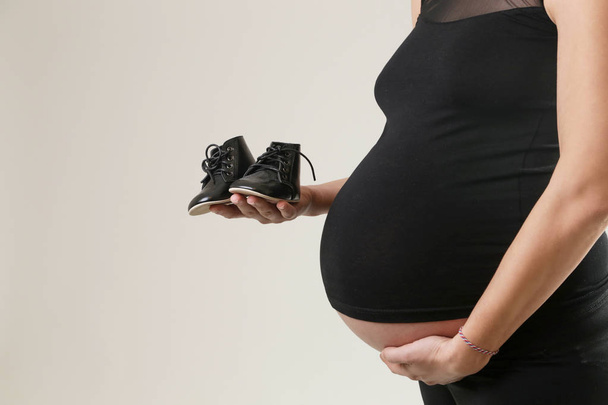 Ayakkabı için bebeği tutan hamile kadın - Fotoğraf, Görsel