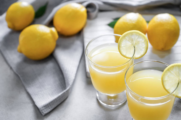 Glasses of fresh lemon juice on light table - Fotoğraf, Görsel