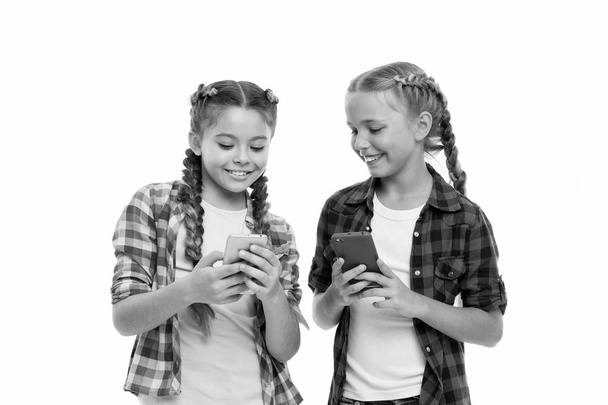 Girls cute small children smiling to phone screen. They like internet surfing social networks. Problem of young generation. Mobile phone and internet addiction or obsession. Mobile phone dependence - Фото, изображение