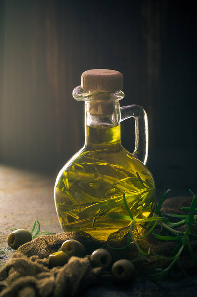 láhev plné olivového oleje sčítání snítky rozmarýnu větev - Fotografie, Obrázek