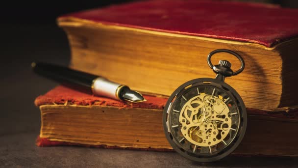 Time lapse orologio da tasca avvolgente collocato accanto al vecchio libro e la penna sul libro nel buio e luce del mattino
. - Filmati, video