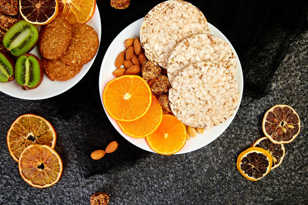 Terveellisiä välipaloja - erilaisia kaura myslipatukka, riisi Crips, manteli, kiivi, kuivattu appelsiini
 - Valokuva, kuva