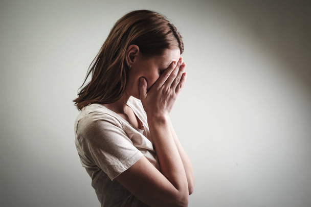 Portrét depresivní ženy, pokrývající obličej rukama, boční pohled - Fotografie, Obrázek
