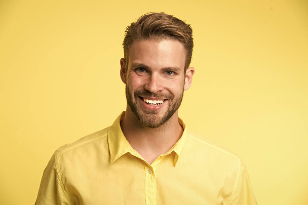 Brilliant smile. Man smiling face posing confidently yellow background. Man shop consultant looks cheerful confident and hospitable. Guy with bristle glad to help you in shop. Sincere emotions - Φωτογραφία, εικόνα