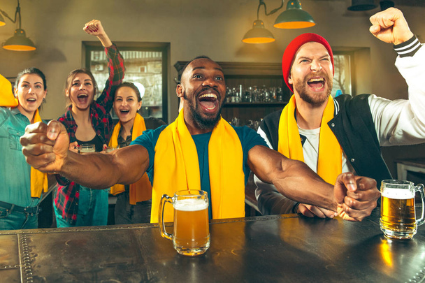 Sport, people, leisure, friendship and entertainment concept - happy football fans or male friends drinking beer and celebrating victory at bar or pub - Foto, immagini