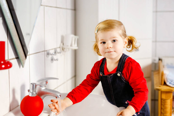 Aranyos kislány kezet mos szappannal és vízzel a fürdőszobában. Imádnivaló gyermek tanulás tisztító testrészek. Reggeli higiéniai rutin. Boldog egészséges gyereket otthon vagy gyerekszobában. - Fotó, kép