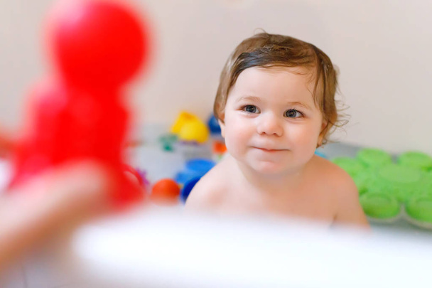 Мила чарівна дівчинка приймає пінисту ванну у ванній. Тодлер грає з гумовими іграшками для ванни. Красива дитина розважається з барвистими іграшками гумок і піни бульбашок
 - Фото, зображення