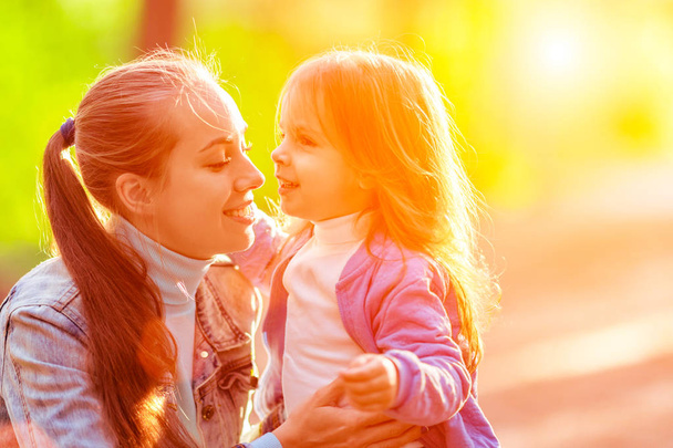 Happy mom with her daughter on a walk in the woods. Summer day, bright sun,  good mood - Foto, Imagen