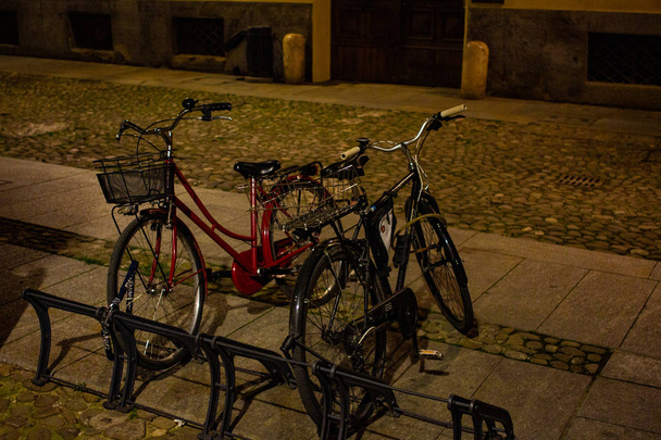 レッジョ ・ エミリアの歴史的な中心部で夜駐車バイク. - 写真・画像